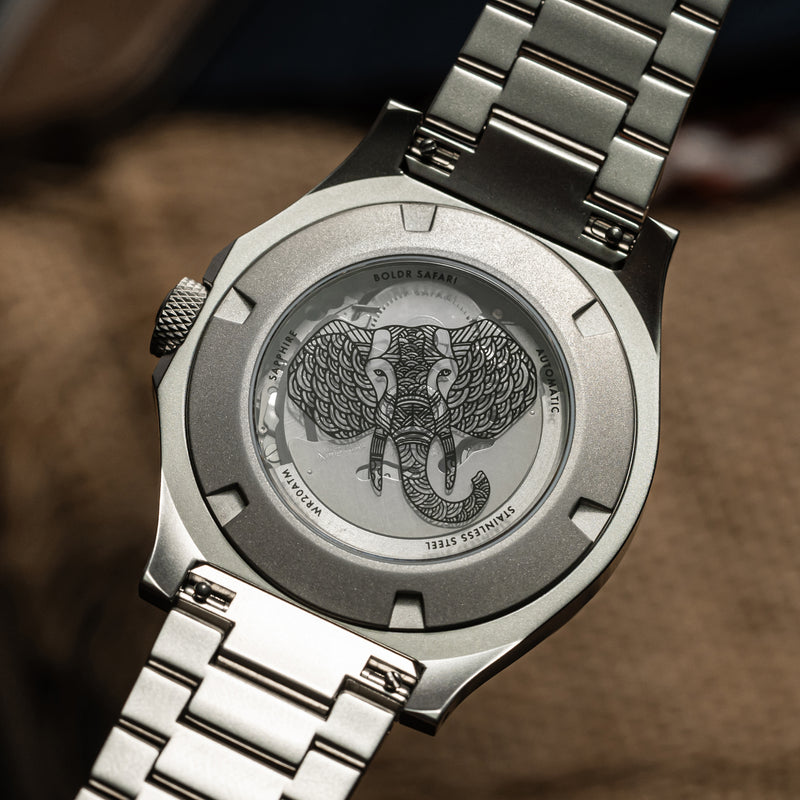 Close-up of a BOLDR Safari watch with an animal printed case back, and a stainless steel bracelet.