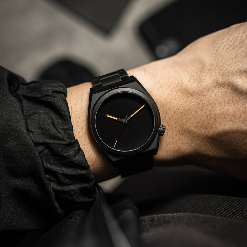 Black watch with matte dial on the wrist showcasing a sleek minimalist and stylish combination